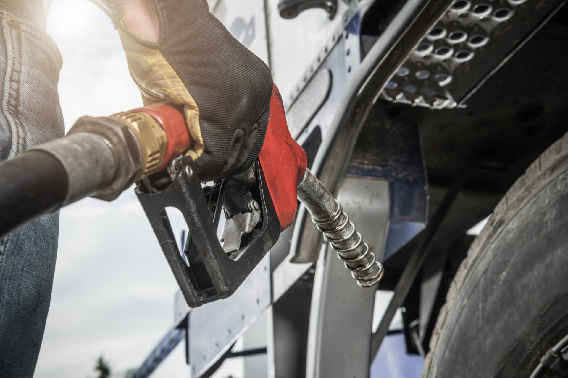 Truck Driver Wearing Safety Gloves Holding Fuel Pump Nozzle in His Hand and Performing Vehicle Refueling Truck Driver Wearing Safety Gloves Holding Fuel Pump Nozzle in His Hand and Performing Vehicle Refueling