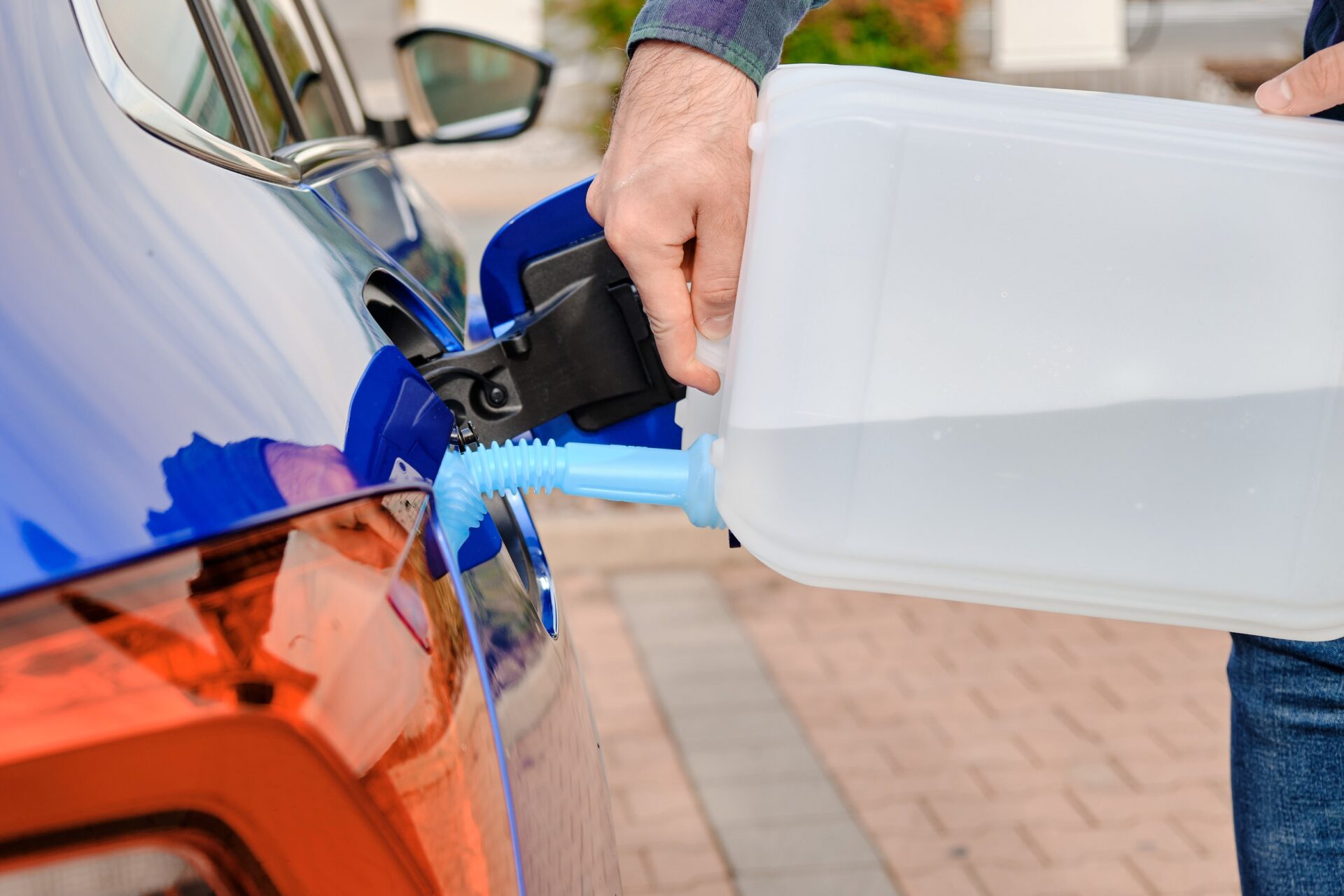 Close up man filling a diesel engine fluid from canister into the tank of blue car Close up man filling a diesel engine fluid from canister into the tank of blue car